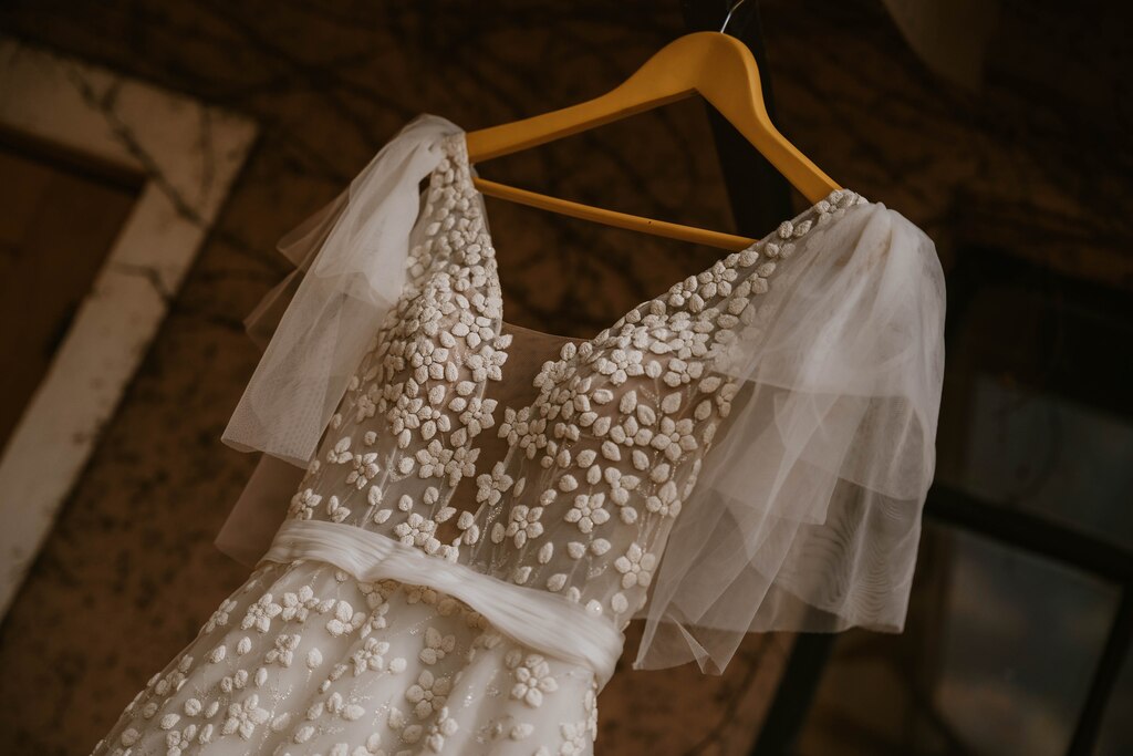vestido de noiva bordado com flores e manga esvoaçante no cabide de madeira