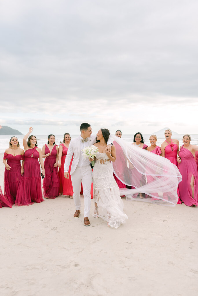 noivos na praia e madrinhas com vestidos cor de rosa em volta