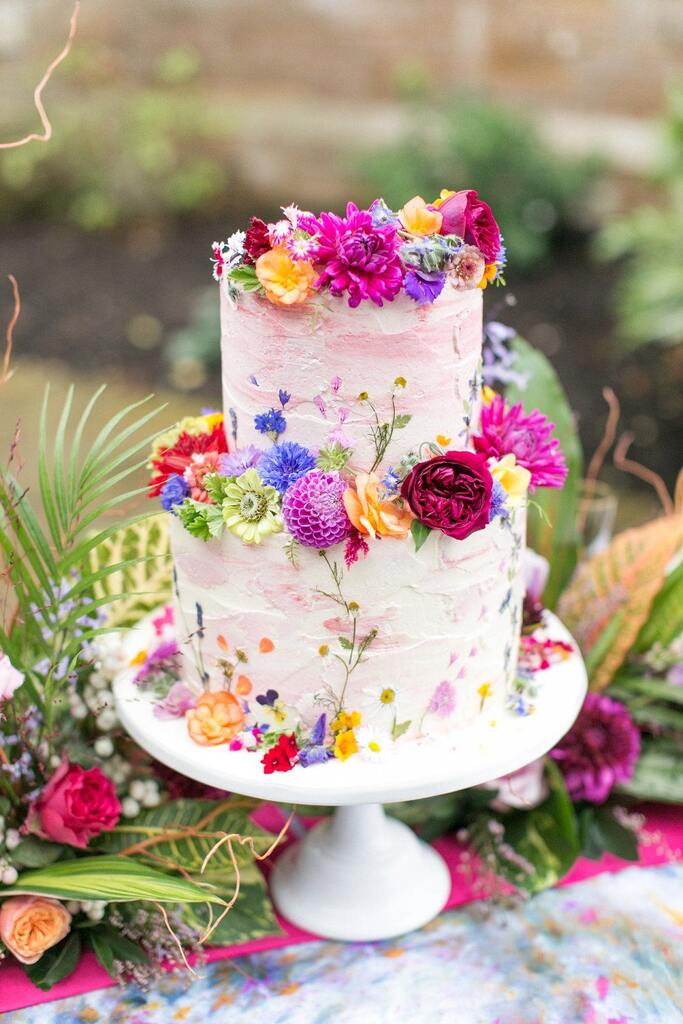 bolo de casamento branco com dois andares com flores coloridas no topo
