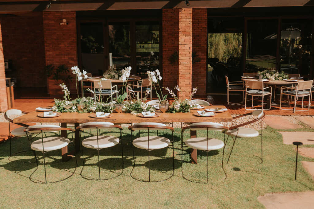 mesa comunitária ao ar livre decorada com flores brancas e orquideas