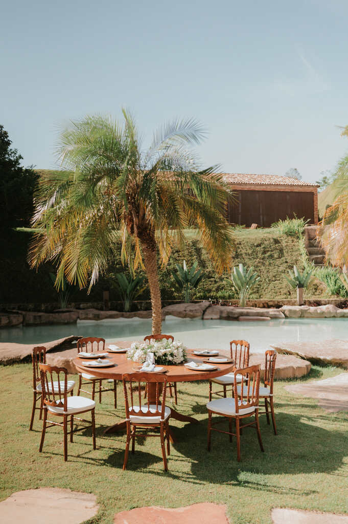 mesa redonda posta ao ar livre perto de palmeira ao lado da piscina