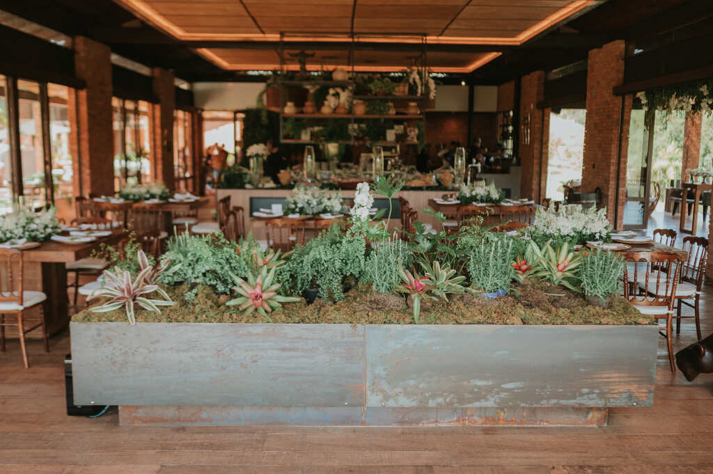 salão com terreiro com plantas cercado por mesas comunitárias