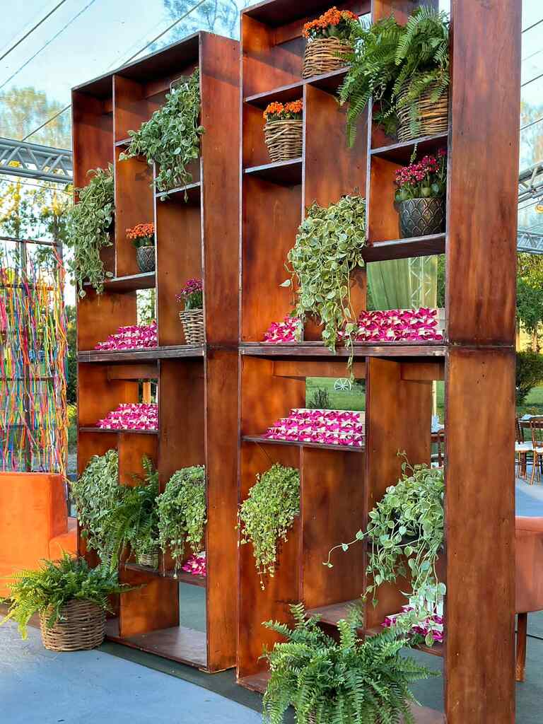estante de madeira com bem-casados com embalagem cor de rosa e plantas