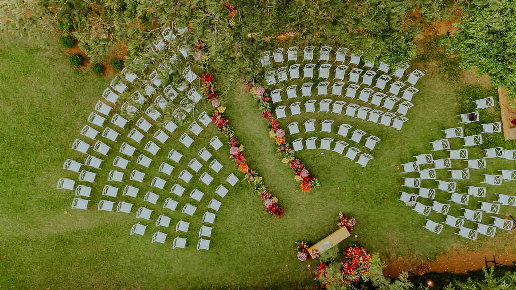 vista de cima de cadeiras no gramado e caminho para o altar com flores coloridas