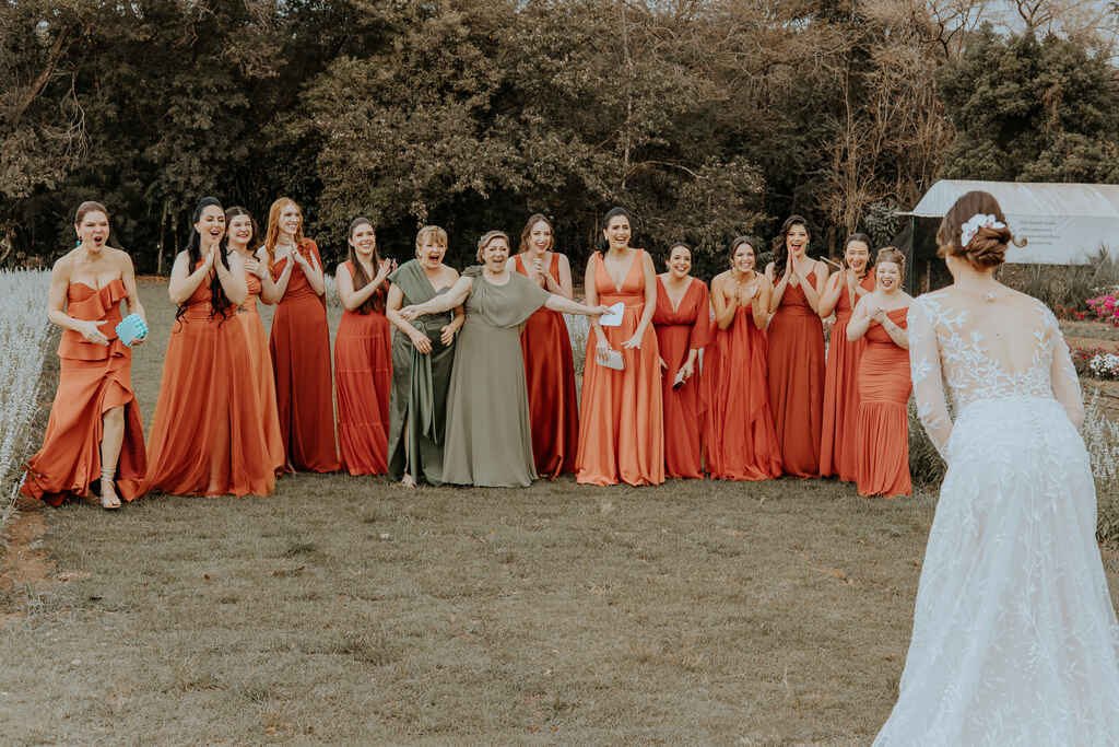 madrinhas com vestidos terracota e mães com vestidos verdes reagindo ao ver a noiva