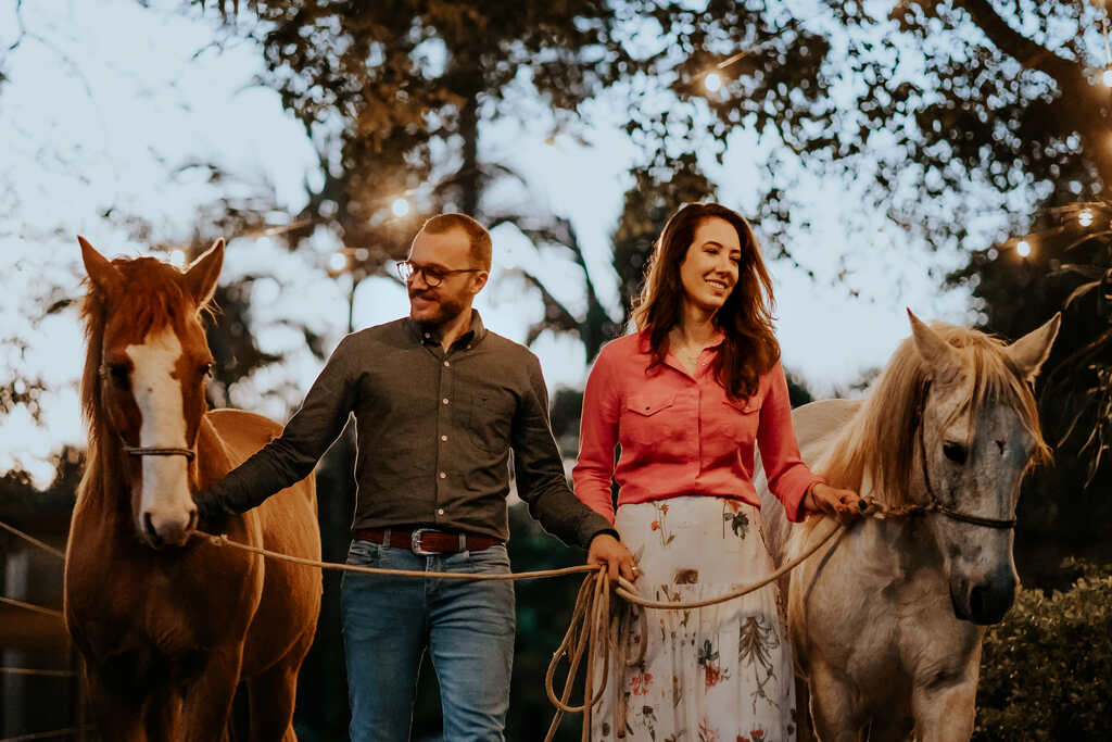casal com roupa country no campo ao lado de cavalos