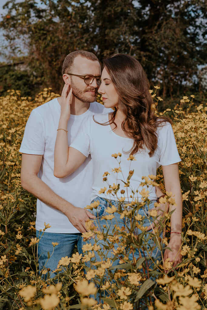 casal abraçado no meio de campo com flores amarelas
