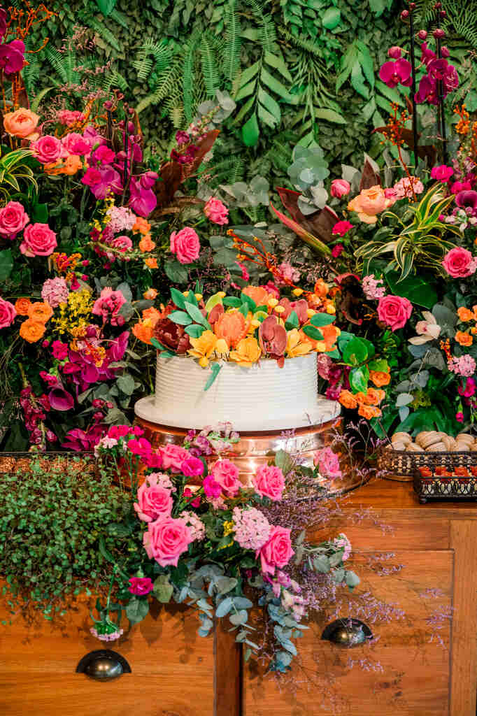 mesa de buffet madeira com bolo de casamento branco com flores coloridas no topo