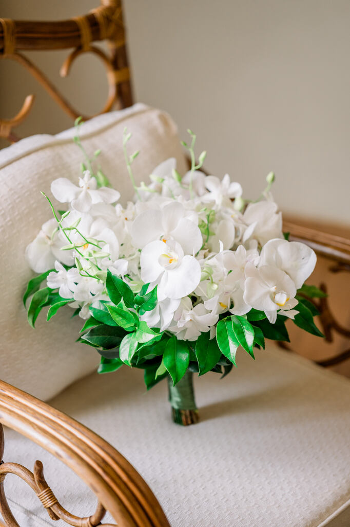 buquê com flore brancas e orquideas em cima de poltrona off white