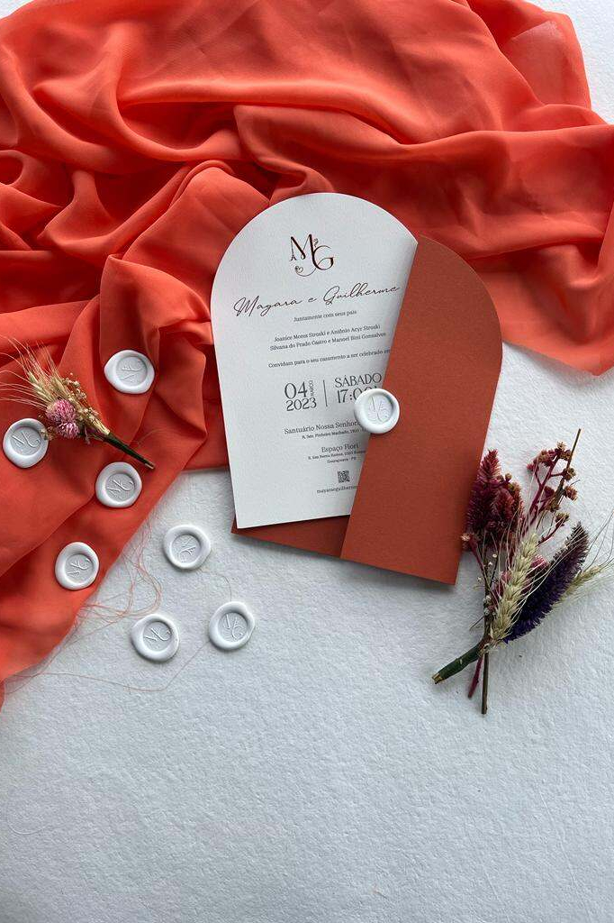 convite de casamento moderno branco com formato arredondado com lacres de cera branco e ao fundo tecido na cor terracota