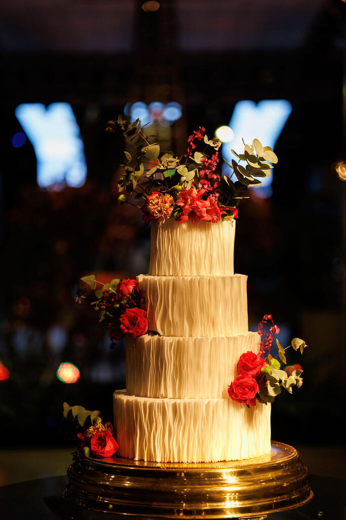 bolo de casamento branco com quatro andares e decorada com flores no topo