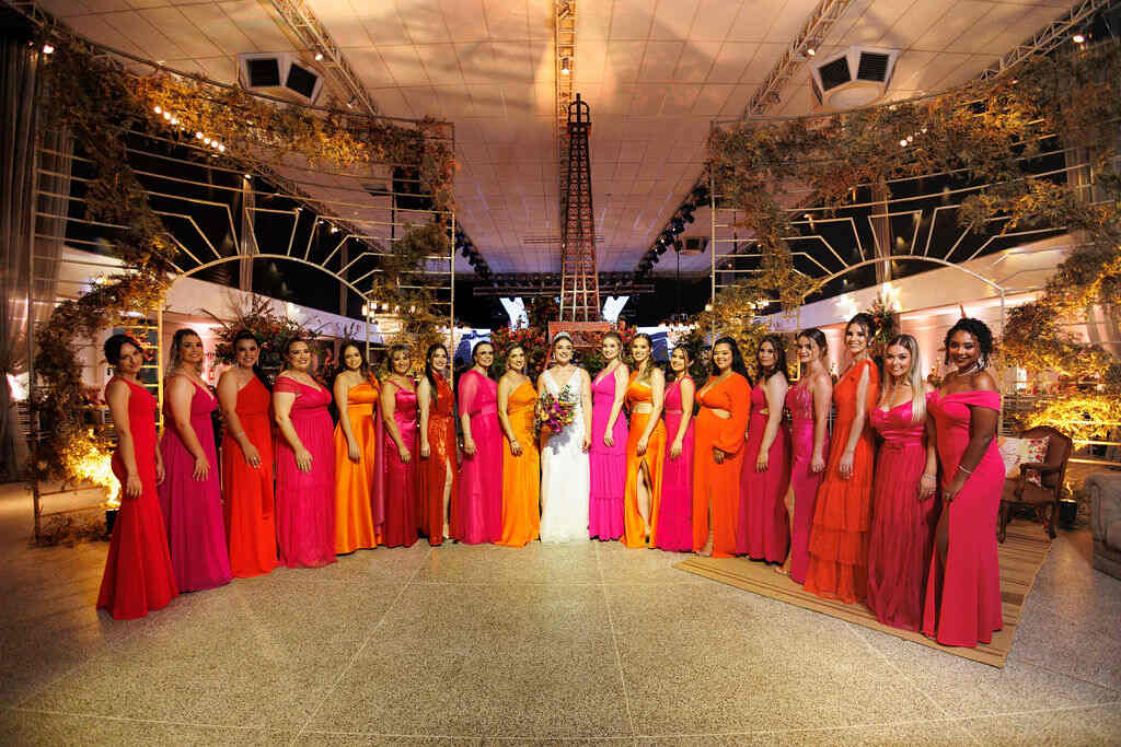 noiva ao lado das madrinhas com vestidos cor de rosa e laranja no salão