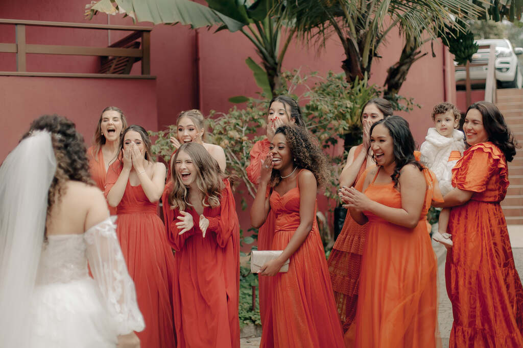 nove madrinhas com vestidos terracota reagindo ao first look com a noiva