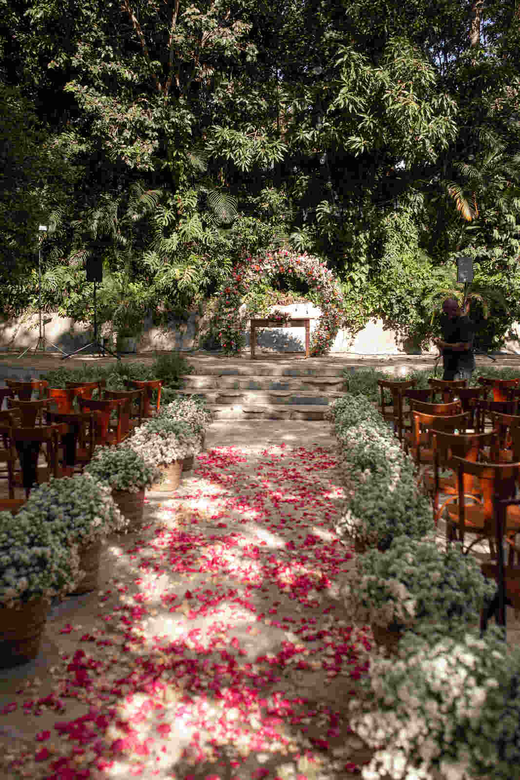 cadeiras de maderias no jardim decorado com flores brancas e pétalas cor de rosa no chão