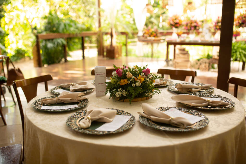 mesa redonda posta com toalha na cor creme e sousplats decorados 