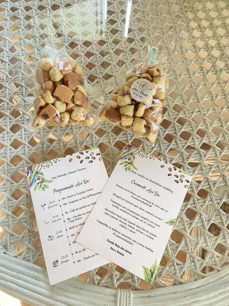 dois pacotes transparentes com bolachas mineiras e papel com programação do casamento com estampa floral
