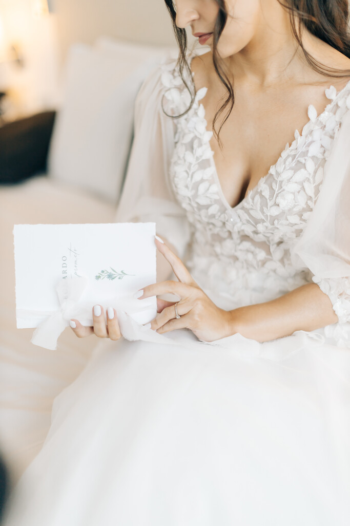 mulher com vestido de noiva com decote em v e manga bufante 3/4 segurando caderno de votos branco