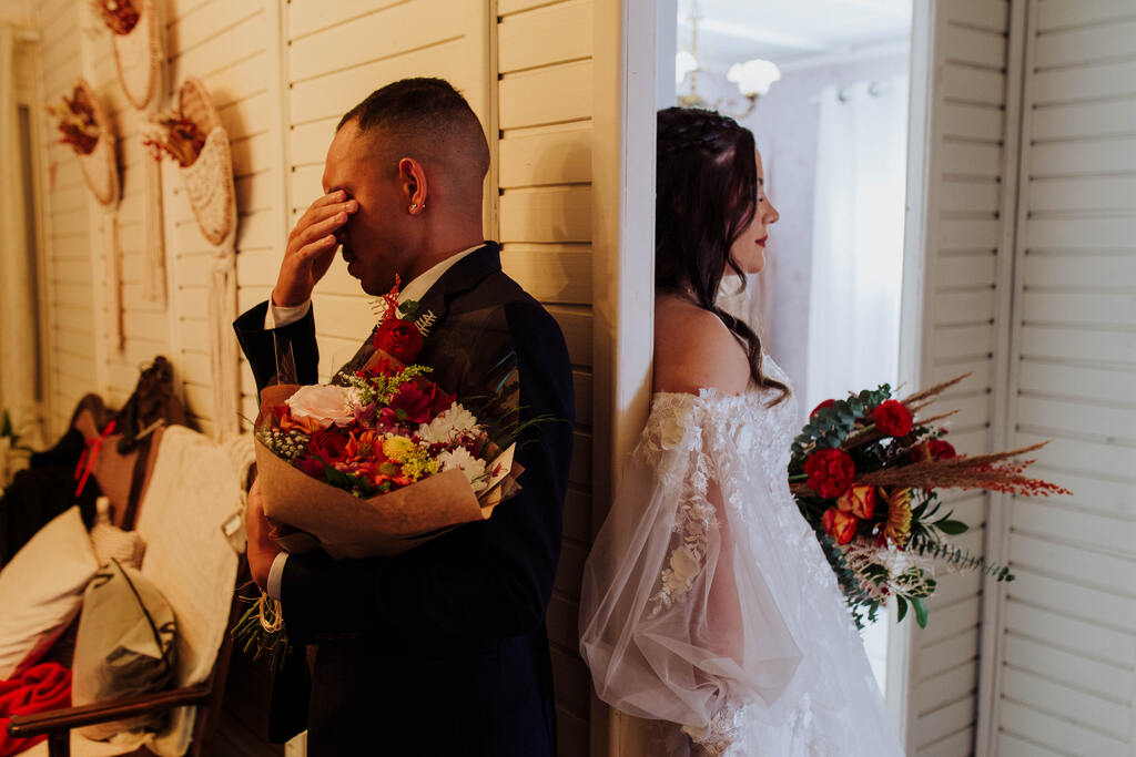 noivo emocionado segurando buquê de flores durante o first touch com a noiva 