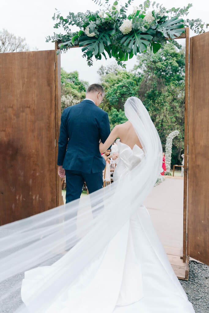 entrada da noiva com véu longo ao lado do pai com terno azul
