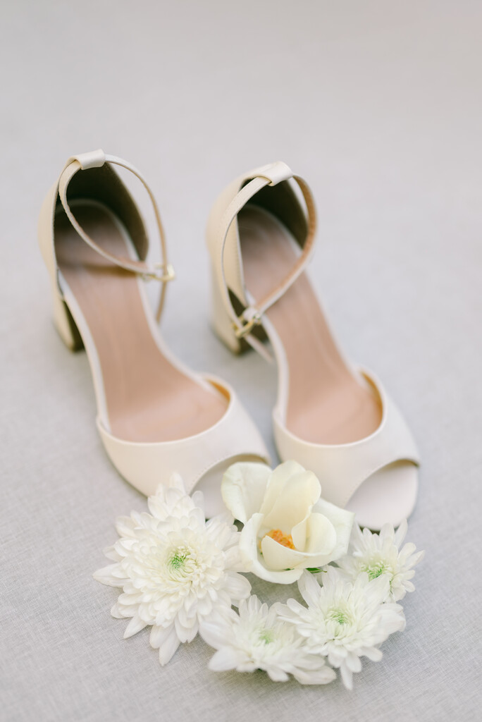 sandália branca peep toe a lado de flores brancas