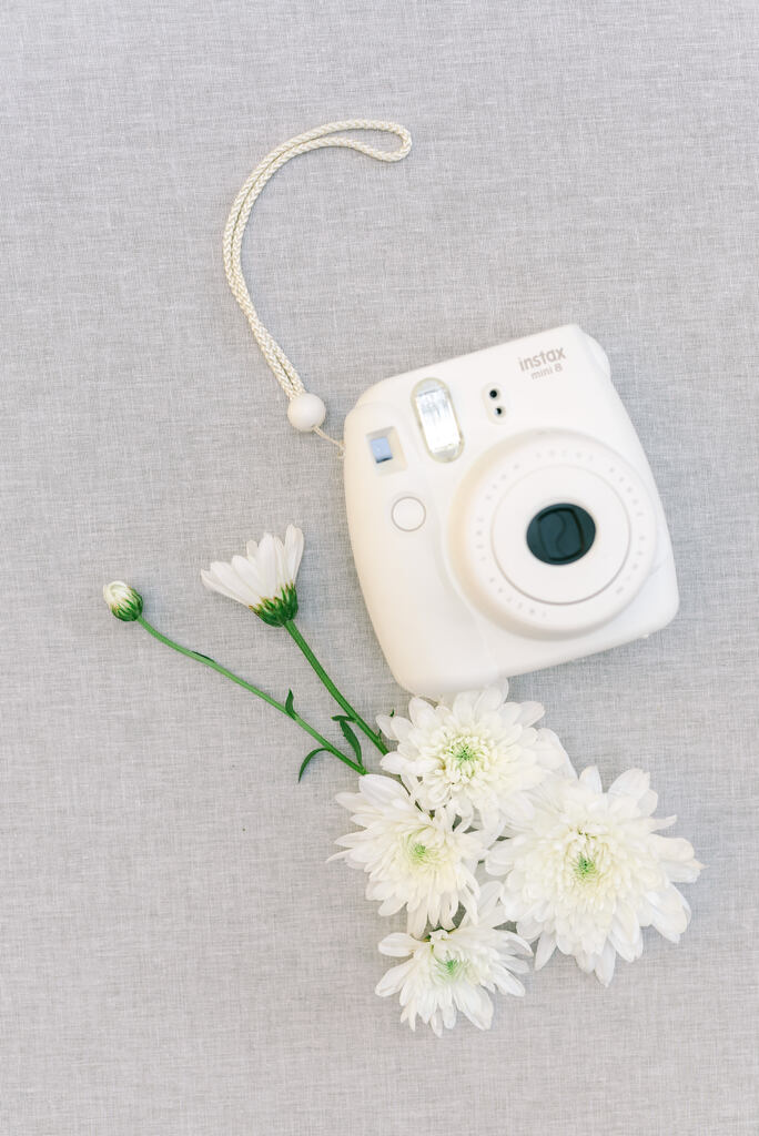 flores brancas ao lado de câmera instatânea branca