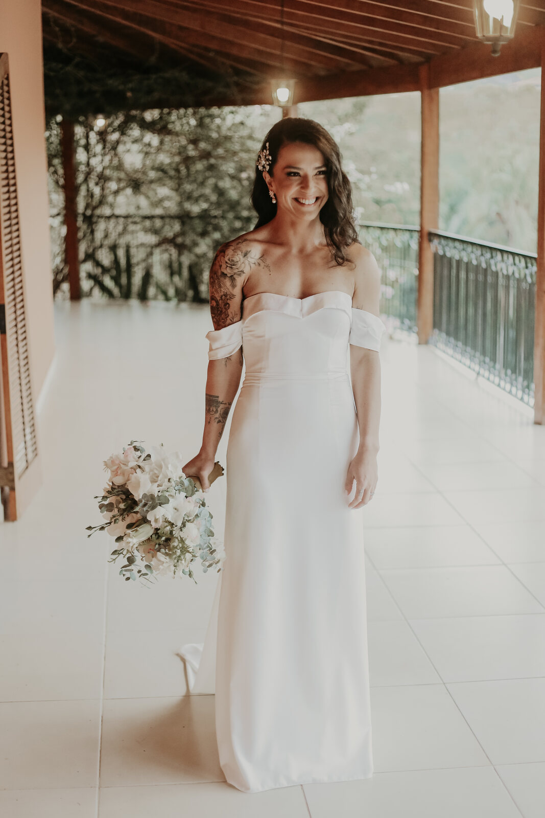 mulher com vestido de noiva minimalista com mangas segurando buquê