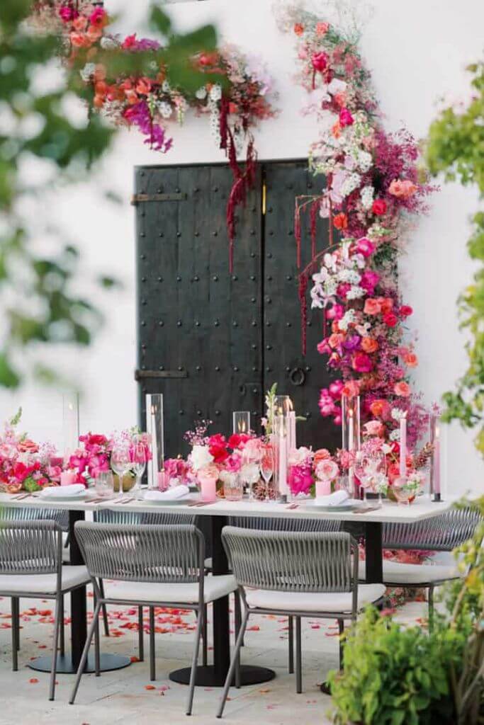 decoração fucsia para casamento com mesa posta e arranjo floral sobre a porta