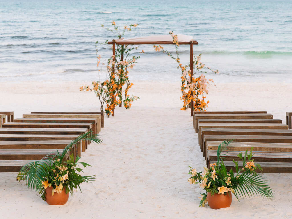 altar simples e rústico com flores laranjjas na praia