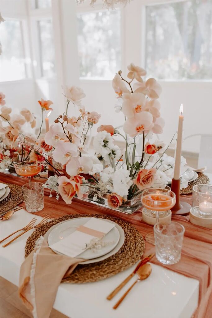mesa posta rústica com velas brancas e arranjos com orquideas brancas e flores