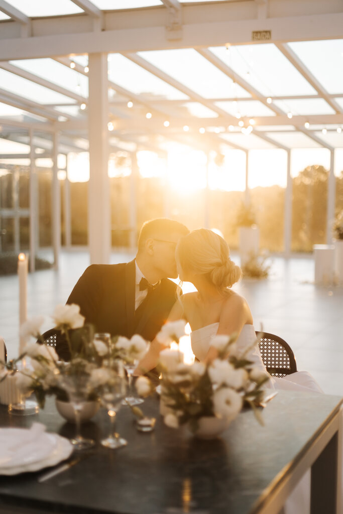 noivos se beijando sentados na mesa durante o por do sol