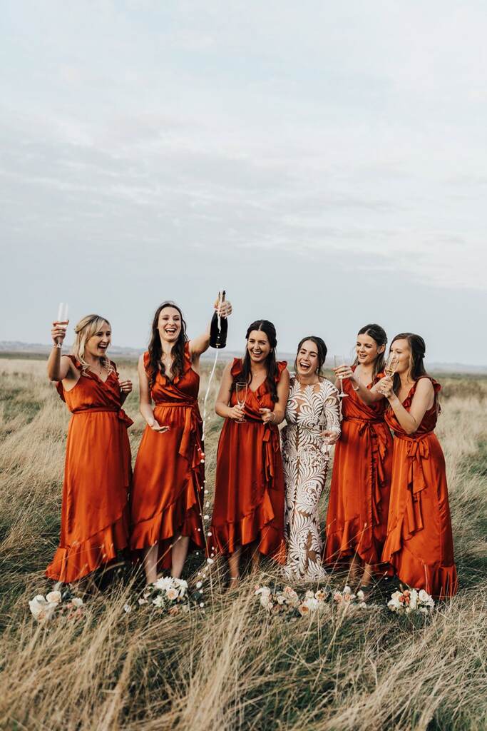 noiva ao lado das madrinhas com vestidos laranja queimado no campo