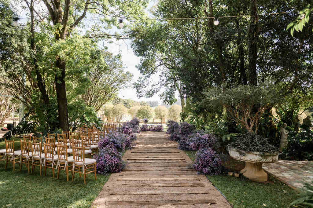 cadeiras ao ar livre com assentos brancos e caminho da noiva decorado com flores lavanda