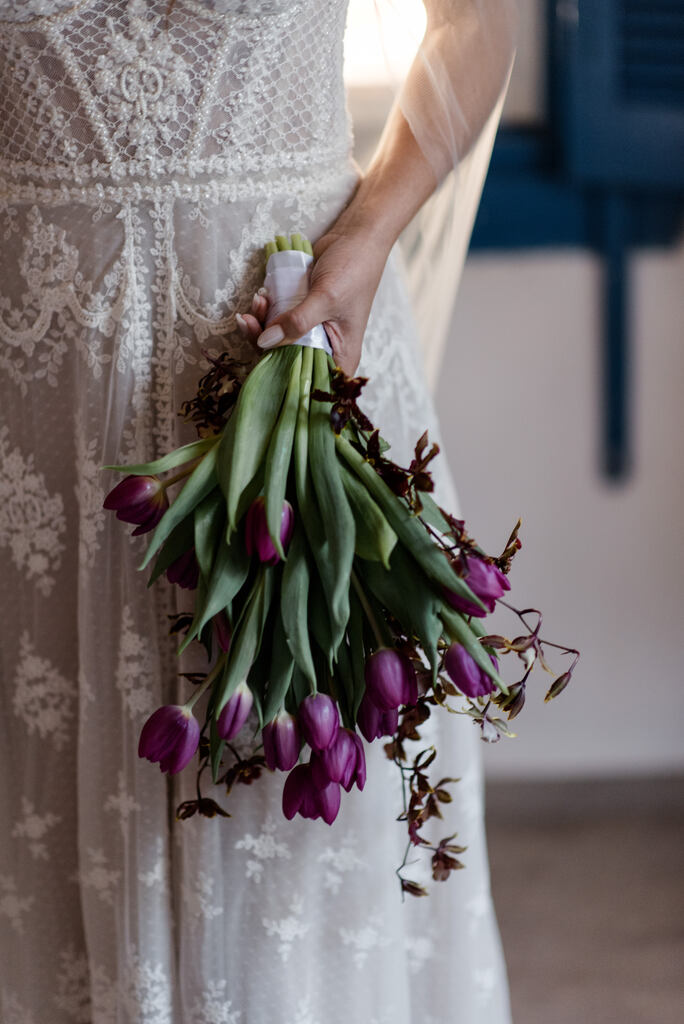noiva com vestido bordado segurando buquê com tulipas roxas