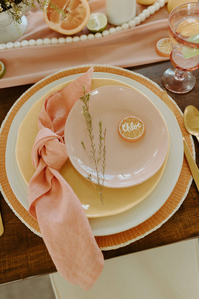 mesa posta com guardanapo rosê e fatia de laranja decorada em cima do prato