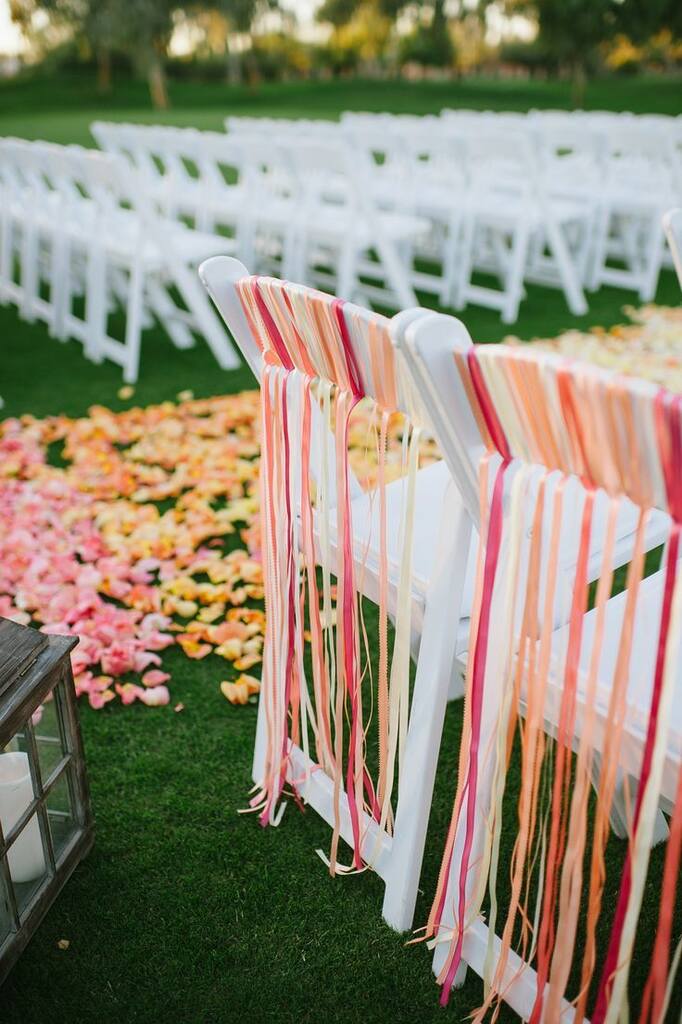 decoração de casamento na praia com cadeiras brancas enfeitadas com fitas rosas