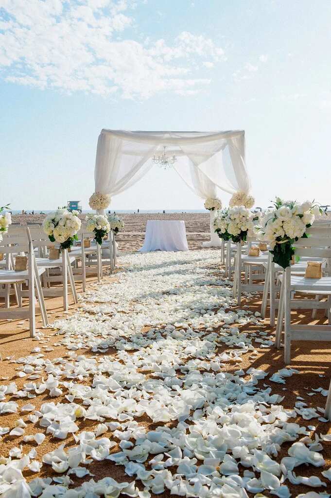 decoração de festa de casamento na praia com altar com tenda branca e flores na areia
