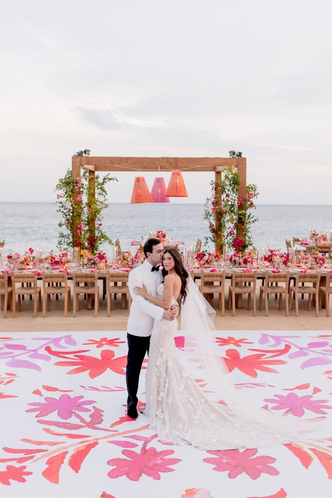 casal dançando no centro de pista de dança branco com estampa floral rosa e lilás na praia