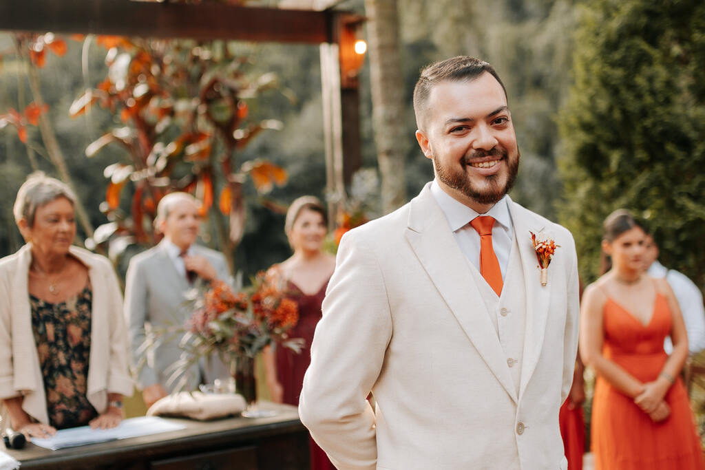 entrada do noivo com terno off white com gravata e lapela laranja acetinada