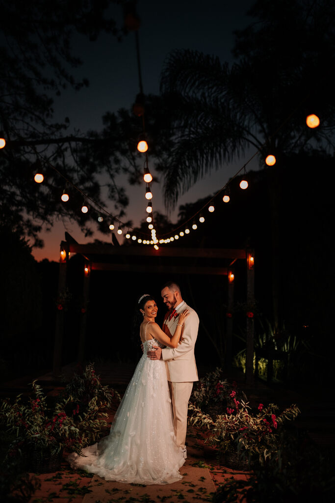 noivos abraçados no jardim à noite decorado com varal de luzes