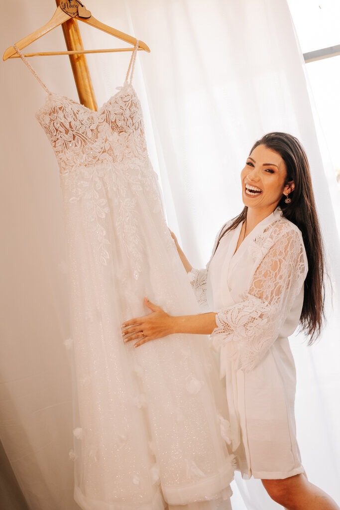 noiva com robe branco segurando vestido de noiva