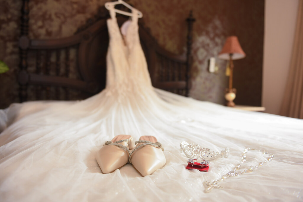 sandália e perfume em cima de vestido de noiva sob a cama