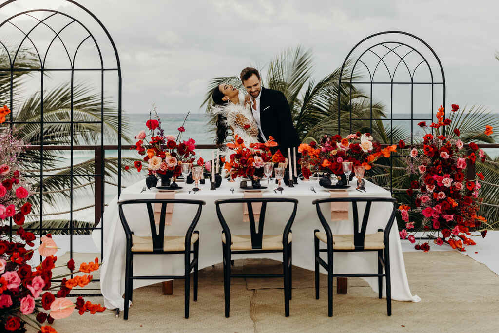 casal abraçado atrás de mesa com flores vermelhas e rosas