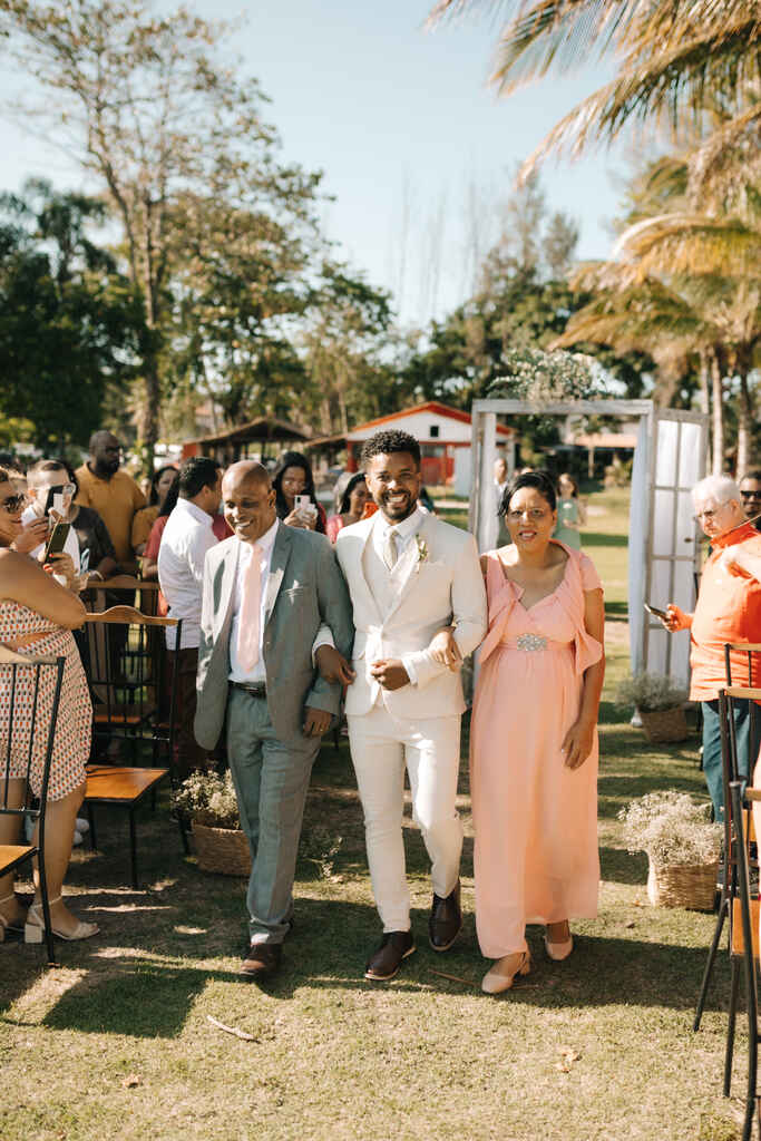 entrada do noivo com o pai com terno cinza e mãe com vestido rosa