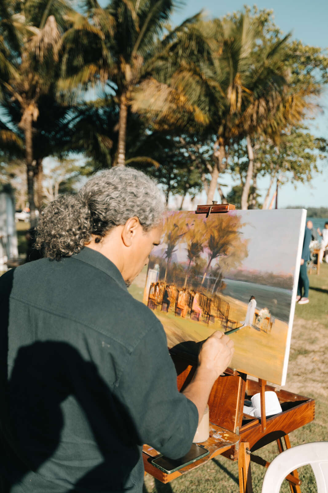 homem com camisa cinza fazendo pintura ao vivo para casamento ao ar livre