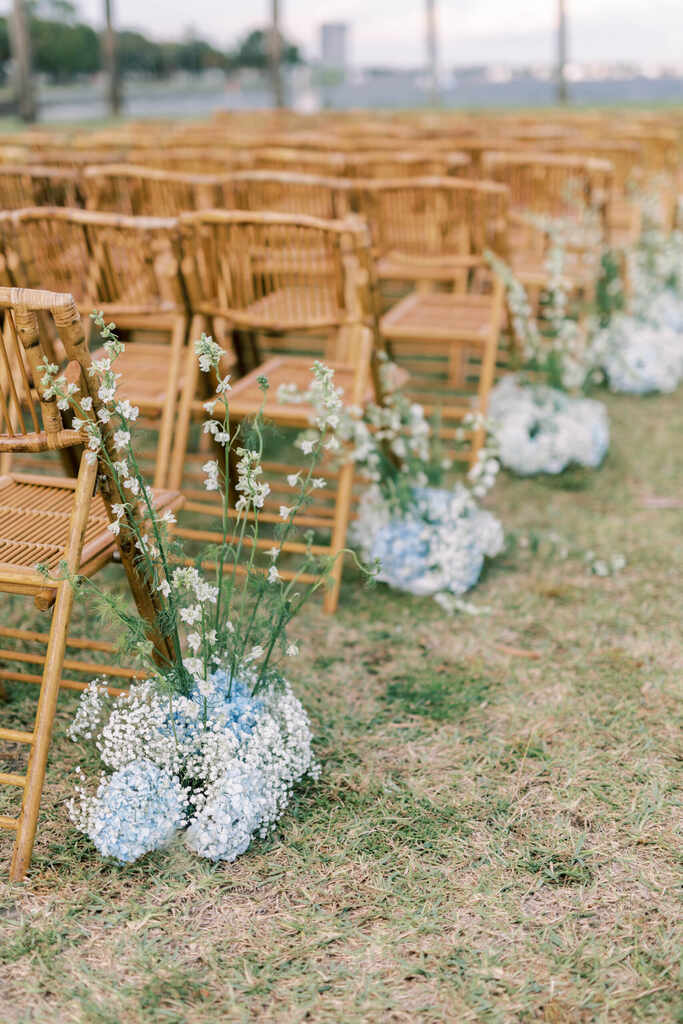 arranjos com flores azuis e flor mosquitinho ao lado das cadeiras de madeira
