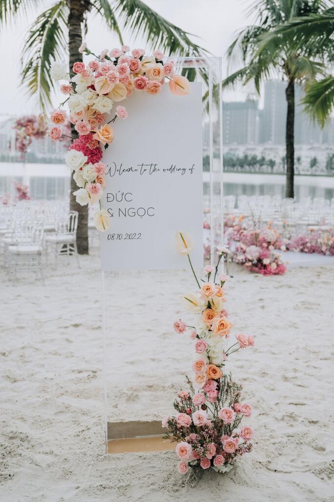 decoração de casamento praiano com placa de boas-vindas brancas com arranjos românticos com flores brancas rosas braancas e laranjas