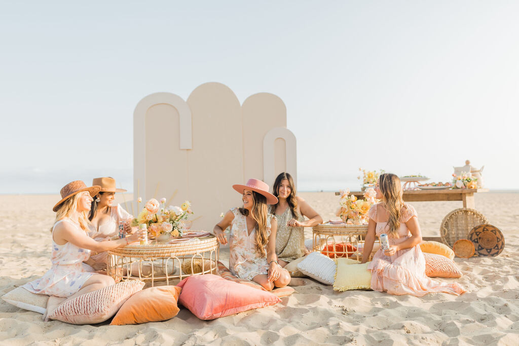 mulheres sentadas em almofadas colirdas em lounge boho e delicado na praia
