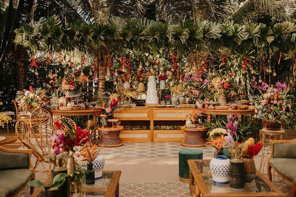 decoração de casamento na praia com mesa do bolo com flores tropicais