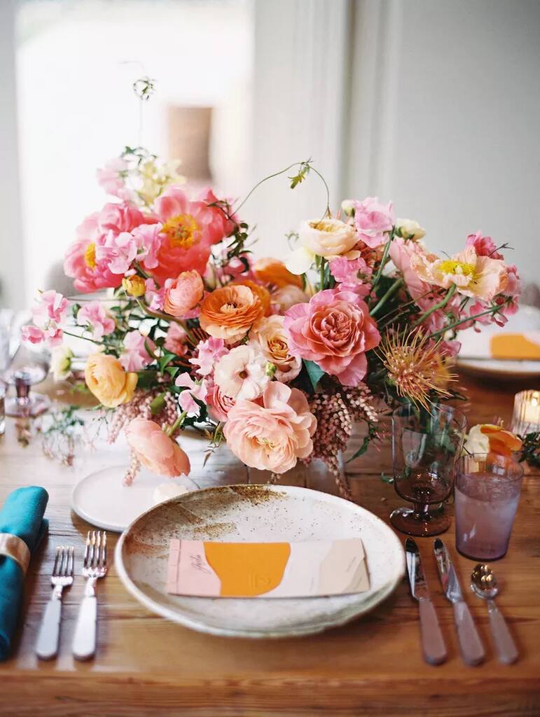 mesa posta com flores rosas larnjas e brancas