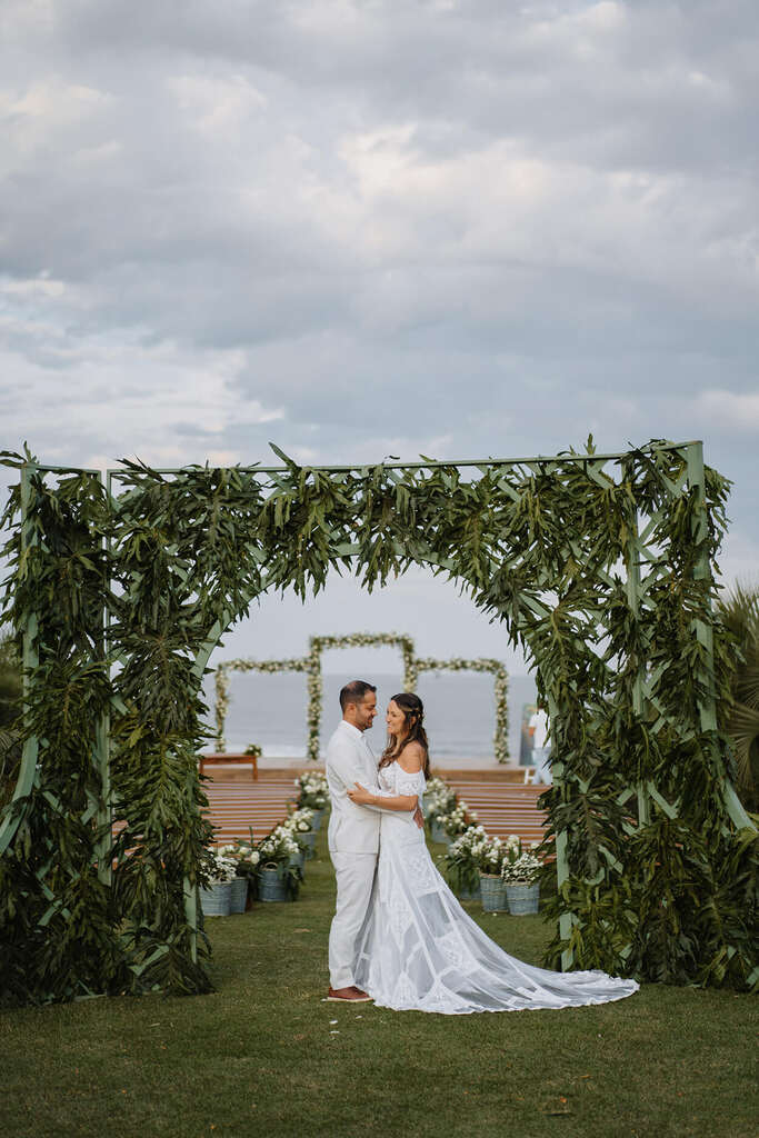decoração de casamento na praia greenery com casal abraçado embaixo de arco
